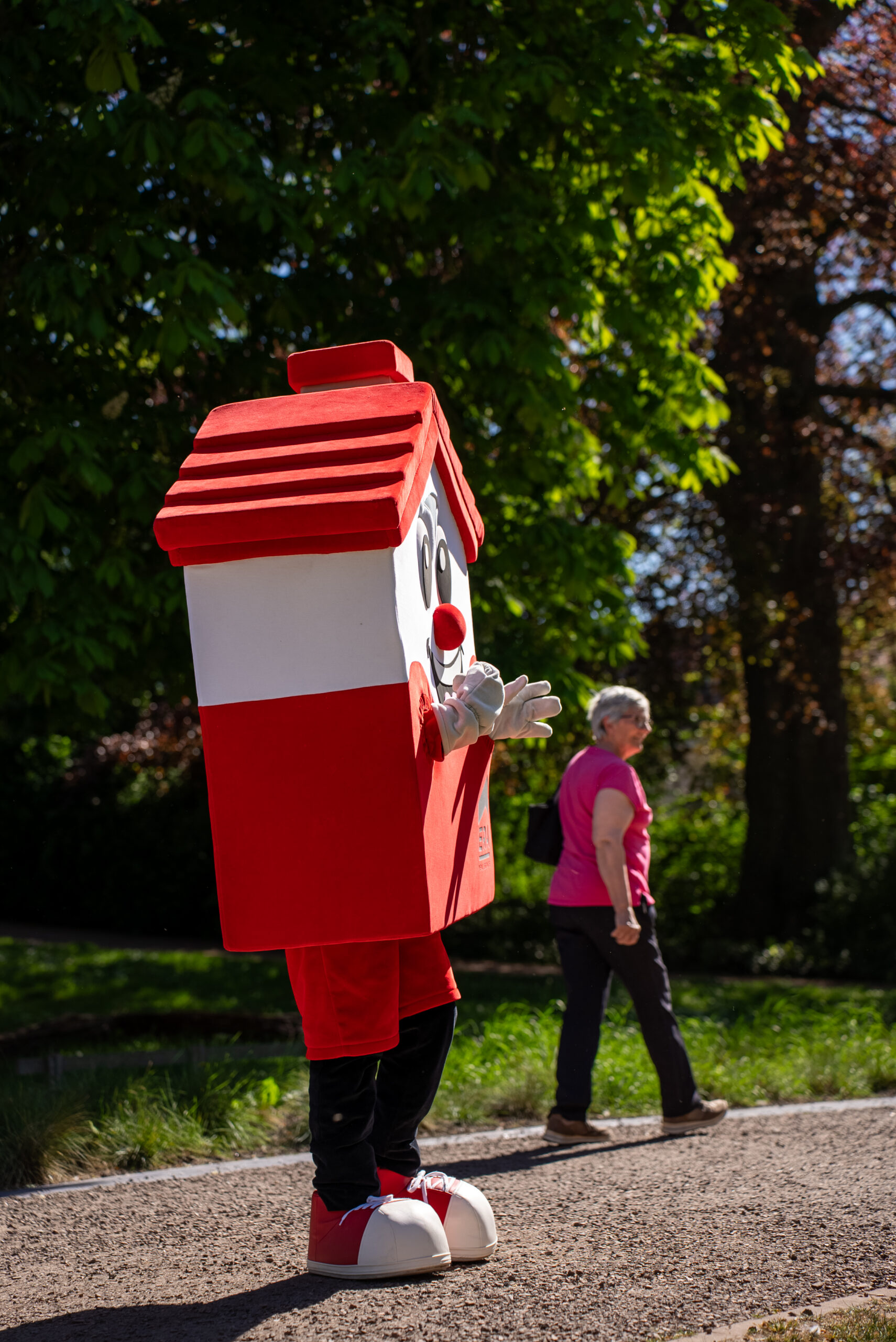 Speelse rode vastgoedmascotte van ERA in vorm van een woning tijdens een evenement in een groene omgeving in West-Vlaanderen. Vastgoed- en syndicexpert in West-Vlaanderen.