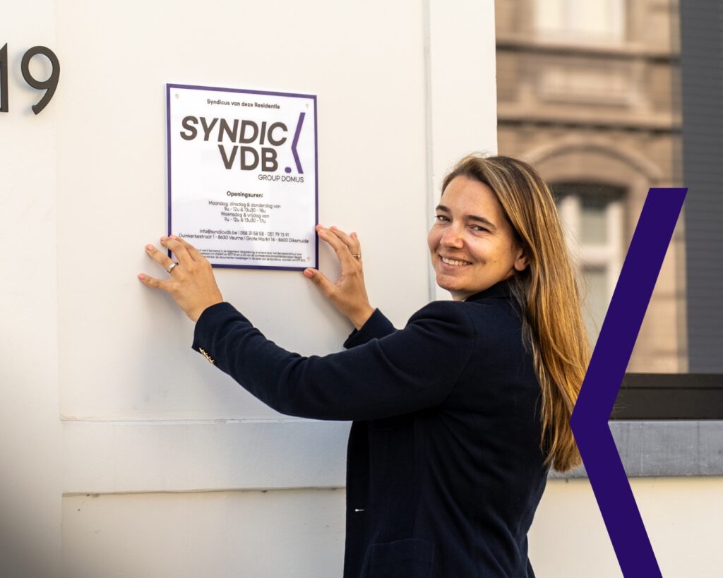 SYNDIC VDB Sanne van Syndic VDB plaatst een syndicusbord bij een residentie in Veurne. Actief in Veurne, Diksmuide, Ieper, Poperinge en Roeselare. Syndicus in West-Vlaanderen